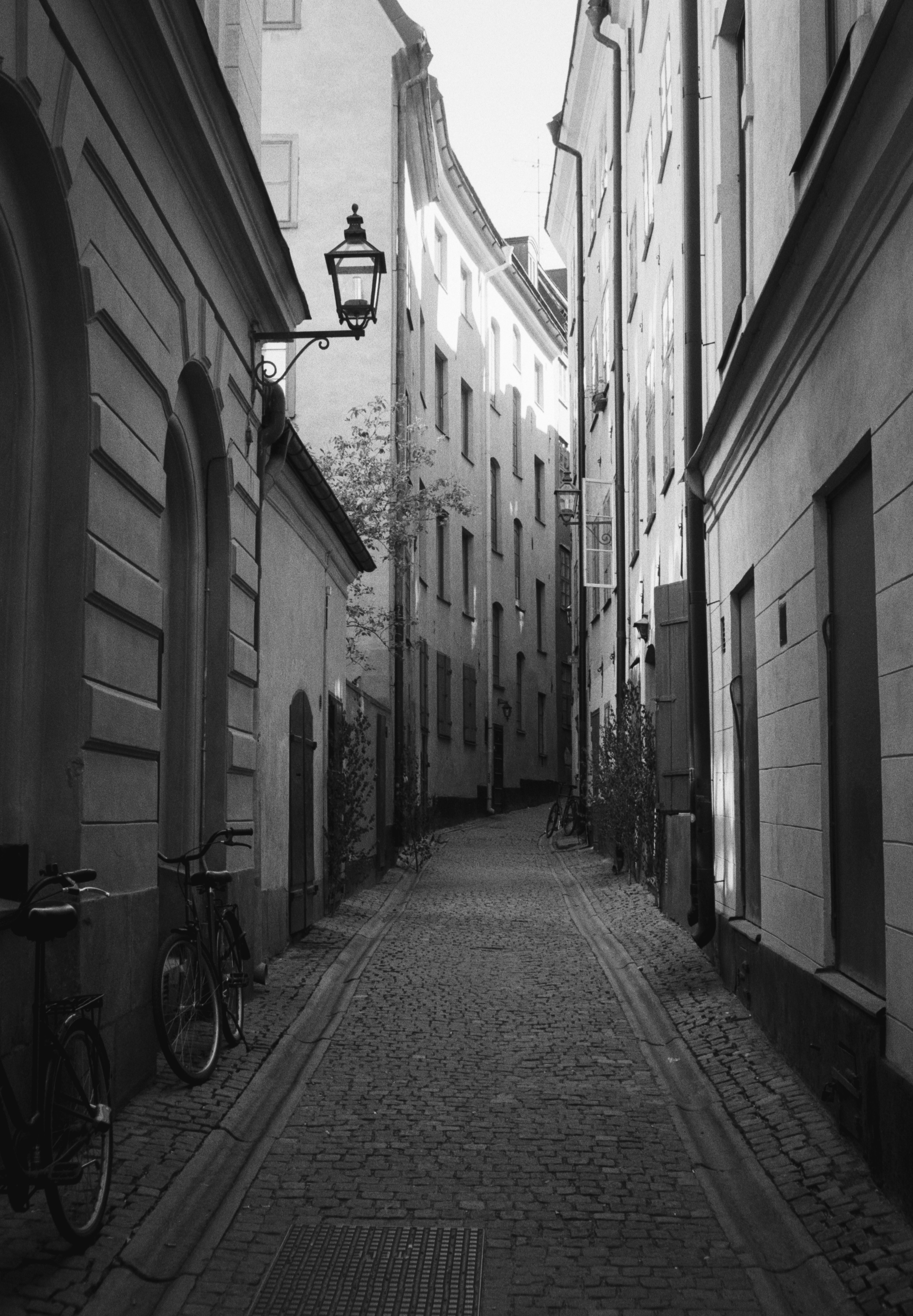 grayscale photo of bicycle parked beside building